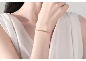 Primer plano de una elegante pulsera minimalista con circones dorados en la muñeca de la modelo