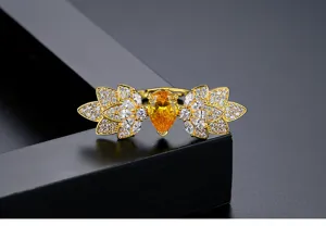Nahaufnahme eines goldenen Rings in Blattform mit birnenförmigem gelbem Kristall.