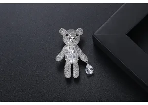 Close-up of a sparkling teddy bear brooch with full crystal paving and a pear-cut drop.