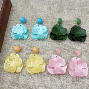 Detail view of flower-shaped resin earrings in blue, green, yellow, and pink