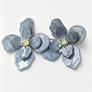 Macro view of elegant grey-blue marble flower stud earrings with gold crystal centers.