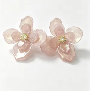 Detailed view of pink pearlescent flower stud earrings with gold stamen centers