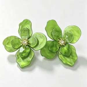 Macro view of green floral earrings with clear crystal centers and marbled texture