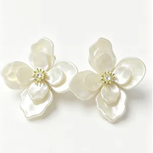 Close-up of elegant pearlescent white flower stud earrings with sparkling center
