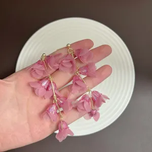 Close-up of pink fabric flower earrings showing delicate petal texture and gold-tone studs
