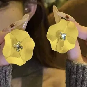Detail view of yellow flower stud earrings with a square crystal center for summer fashion