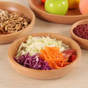 Round beech wood salad bowl with fresh vegetable salad and wooden fruit plates