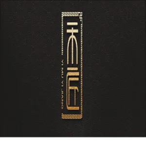 Detalle del logotipo de la marca Yi Mu Yi Jiang en pan de oro sobre un fondo negro texturizado