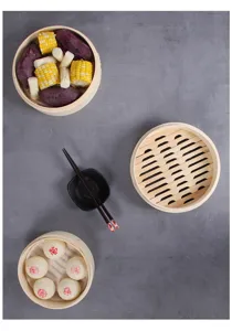 Top view of three bamboo steamers with buns, corn, and sweet potatoes on a gray background