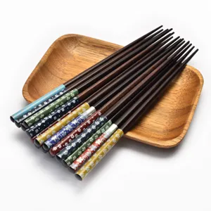 Japanese-style pointed wooden chopsticks with colorful floral patterns on a wooden tray