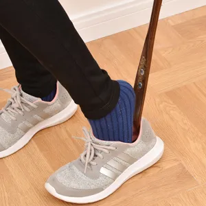 Long 75cm professional wooden shoehorn helper shown in a realistic footwear usage scenario