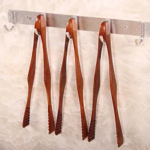 Professionele set van drie handgemaakte houten voedseltangen aan een metalen wandrek
