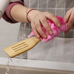 Natural long handle bamboo kitchen spatula being washed with a pink microfiber cloth