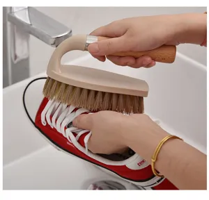 Action shot of wooden cleaning brush scrubbing a red canvas shoe in a sink