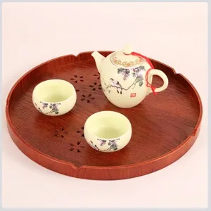 Japanese style round wooden tray with floral ceramic teapot and two teacups for home