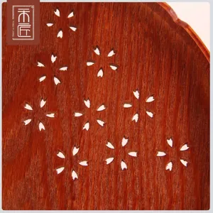 Detailed macro view of dark wood tray with elegant cutout cherry blossom pattern