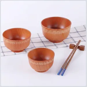Ensemble de trois bols en bois japonais avec motifs ethniques et baguettes sur table