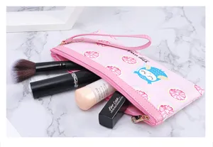 Detailopname van het roze make-uptasje met uilenpatroon en inhoud.