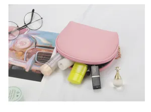 Close-up of a pink semi-circular cosmetic bag filled with various makeup essentials