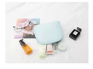 Lifestyle view of light blue shell-shaped travel makeup bag with various cosmetics