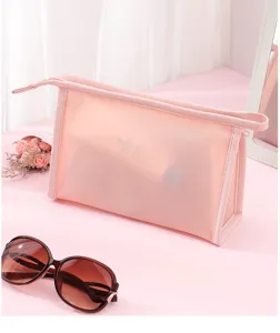 Detail view of pink frosted PVC waterproof cosmetic bag with sunglasses and mirror.