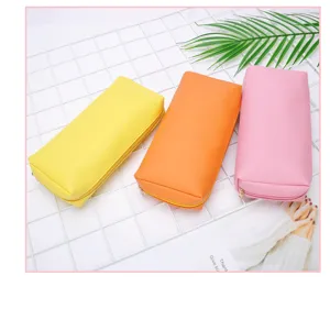 Drei bunte PU-Leder-Taschen in Pink, Orange und Gelb auf einem weißen Gitterregal