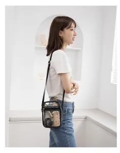 Side view of a clear PVC crossbody makeup bag worn by a model in casual white outfit.