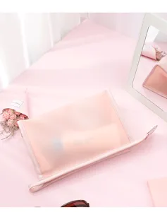 Detail of semi-transparent pink PVC makeup bag on a minimalist vanity.