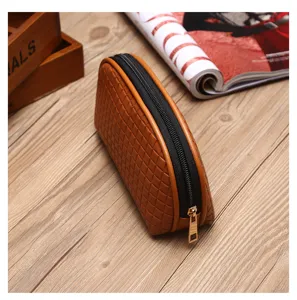 Nahaufnahme einer braunen Make-up-Tasche mit Webmuster und goldenem Reißverschluss auf Holz
