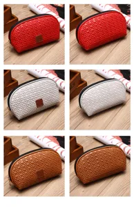Grandi borse cosmetiche intrecciate in rosso, beige e marrone con chiusura lampo
