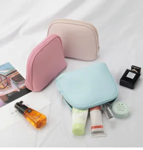 Macro view of pastel-colored shell cosmetic bags with toiletries on white silk