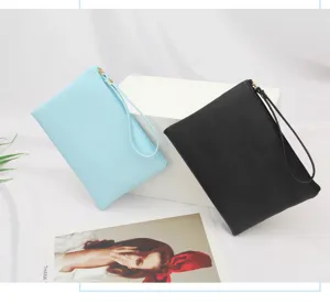 Sky blue and black PU leather makeup pouches leaning on white blocks with wrist straps