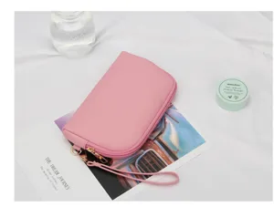 Detalle de un mini neceser de maquillaje rosa de cuero PU con una práctica correa de mano.