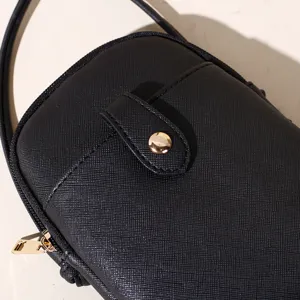 Close-up of a black textured Saffiano leather phone crossbody bag with gold hardware