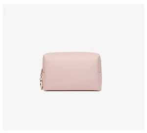 Minimalist pink PU leather makeup bag with gold ring zipper detail on plain background
