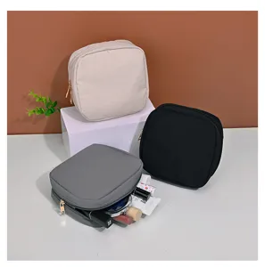 Macro view of three compact square makeup pouches in beige, black, and grey colors.