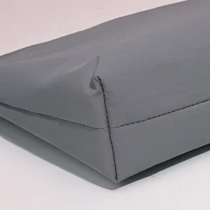 Detalle de costura de un neceser de nailon gris sólido con acabados de alta calidad