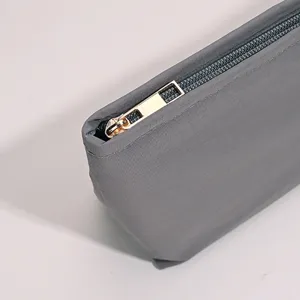 Primer plano de neceser de nailon gris con detalle de cremallera dorada