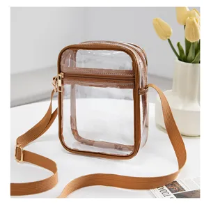 Clear PVC waterproof crossbody bag with adjustable brown strap shown in a stylish home setting