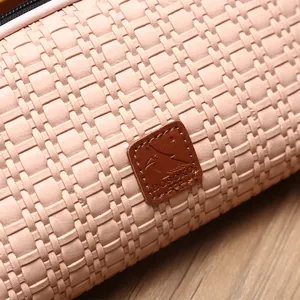 Dettaglio di una grande borsa cosmetica intrecciata rosa con logo in pelle premium