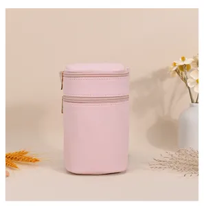 Macro detail view of a pink PU leather cylindrical crossbody bag with double gold zippers