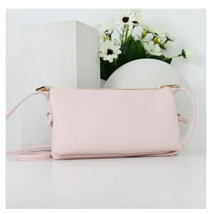 Detailed macro view of light pink crossbody phone bag with saffiano leather texture and gold zipper