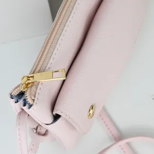 Close-up of pink crossbody bag with gold zipper and textured saffiano finish.