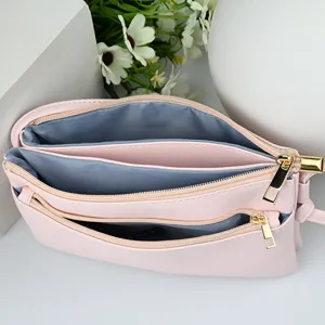 Elegant light pink PU leather crossbody phone bag featuring three spacious zipper pockets