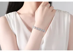 Detalle de pulsera plateada en forma de corazón con circonitas en la muñeca