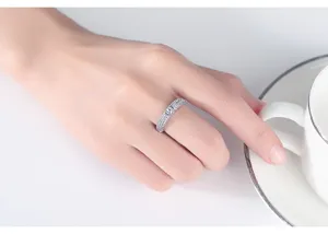 Close-up detail of silver micro-paved zircon ring on finger with white coffee cup.