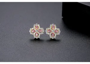 Macro view of delicate pink zircon four-petal flower stud earrings with gold finish