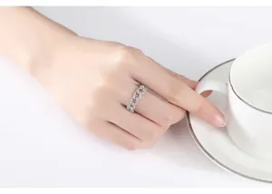 Detalle de un anillo de cadena cubana plateado con circonitas en una mano.