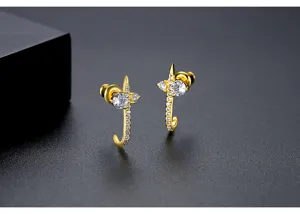 Close-up of golden J-shaped stud earrings with sparkling cubic zirconia stars
