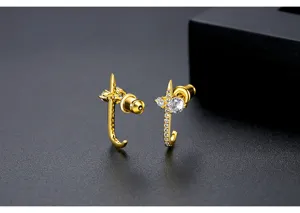 Close-up detail of gold-plated J-shaped stud earrings with sparkling cubic zirconia.